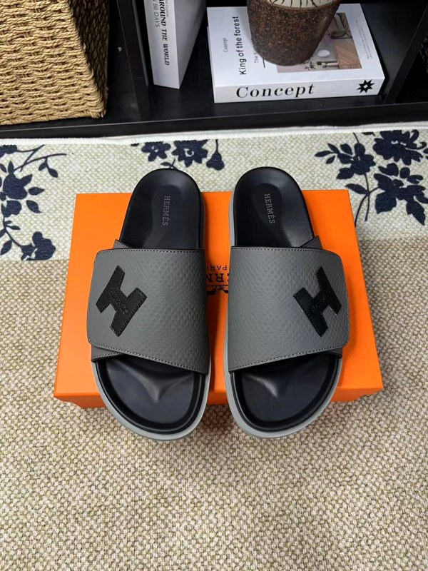 Hermes black leather slides with a rubber outsole, listed in a wide unisex size run