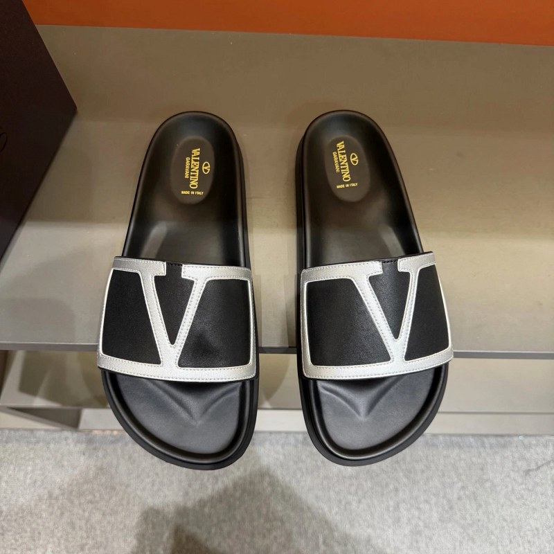 Valentino black leather flat slide with a metal logo and rubber outsole
