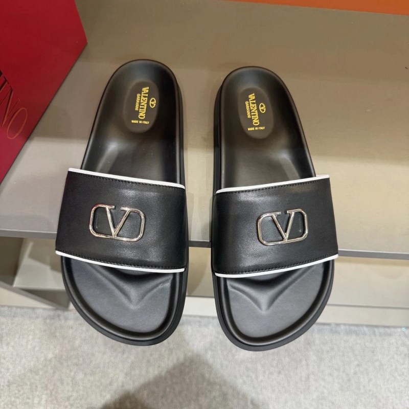Valentino black flat slide with metal logo, listed in calf leather on a rubber outsole